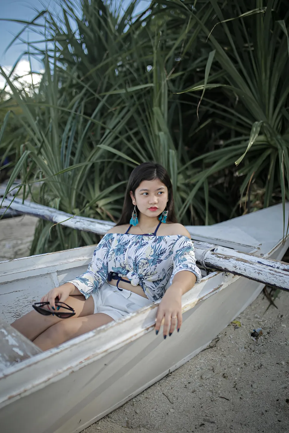 Ellidiethe Rielle in floral top seated in small boat on beach