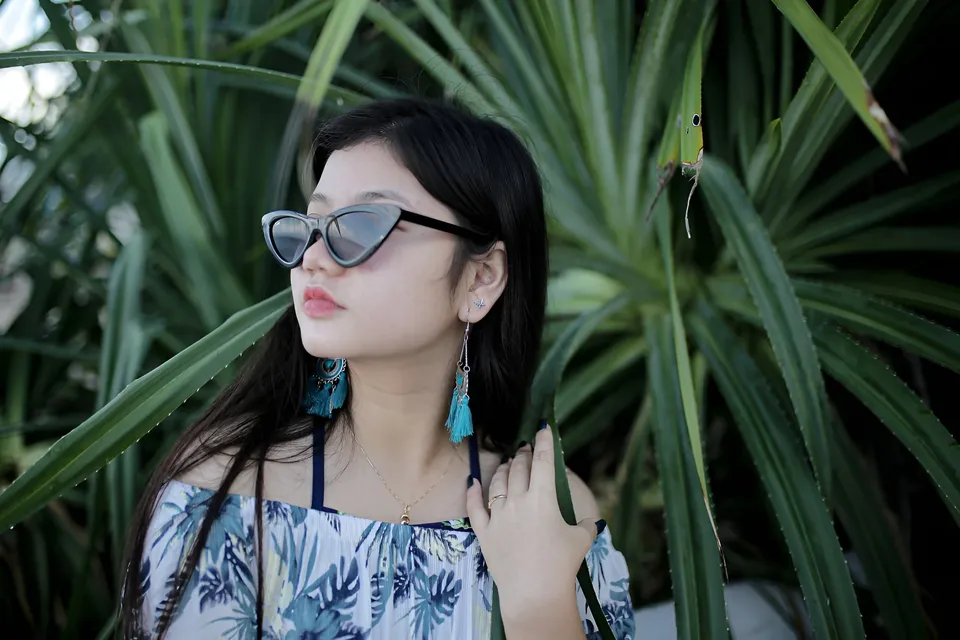 Ellidiethe Rielle wearing sunglasses and floral top among green plants