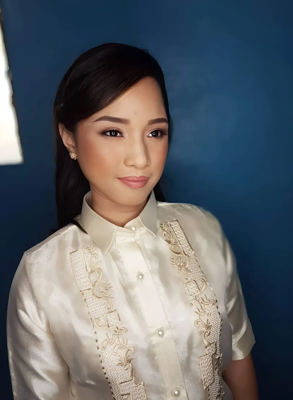 Eunice Gubot in white embroidered shirt poses against blue background