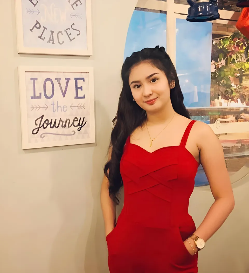 Eunice Lois in red dress standing beside framed wall art