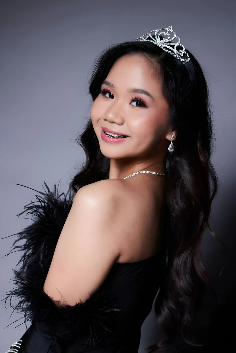 Faye Ramos in black feathered top with tiara and earrings