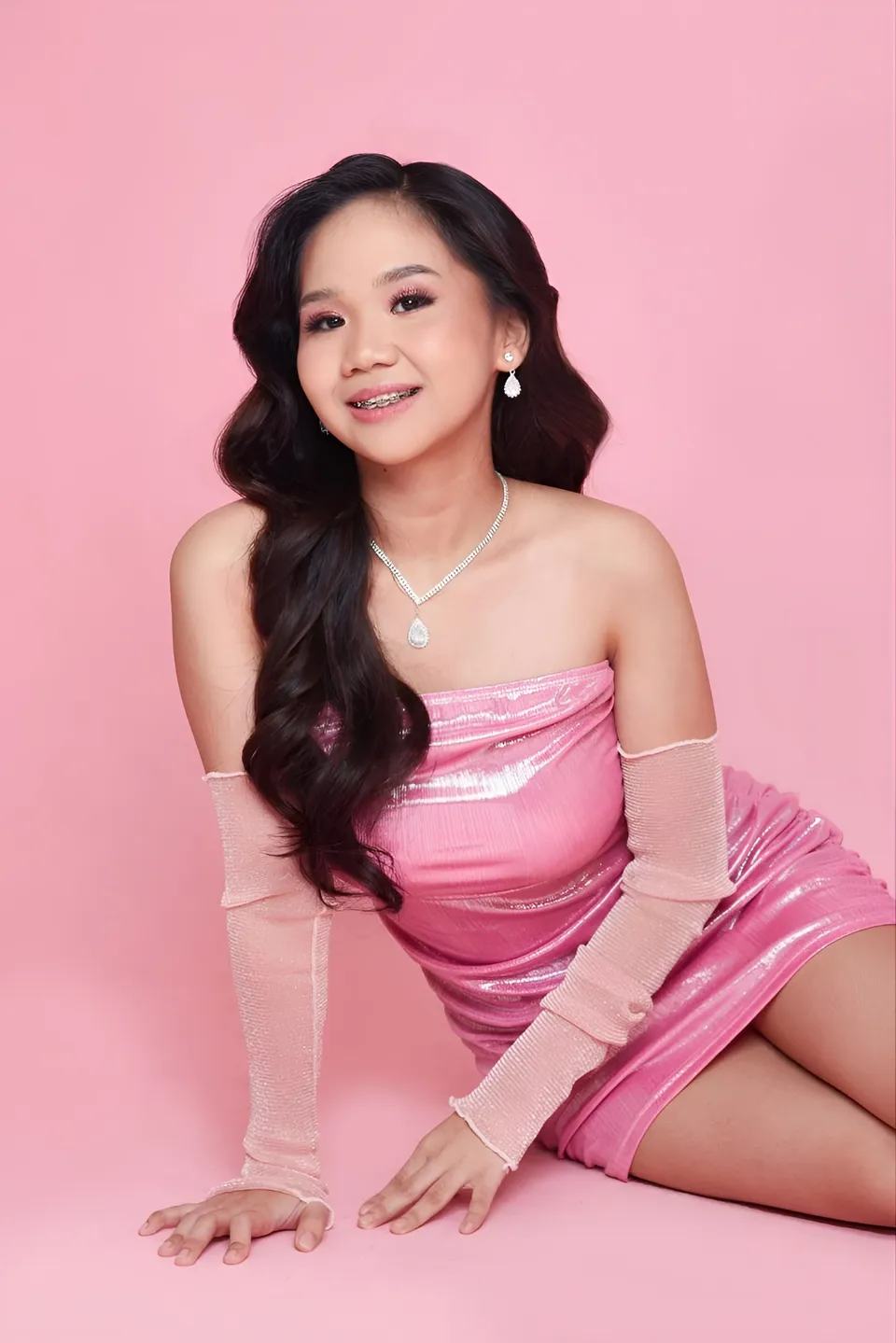 Faye Ramos in pink dress seated on pink surface