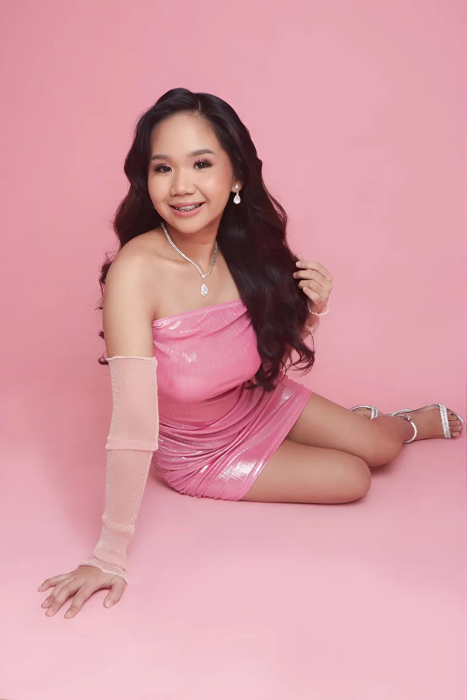 Faye Ramos in pink dress sitting on pink surface