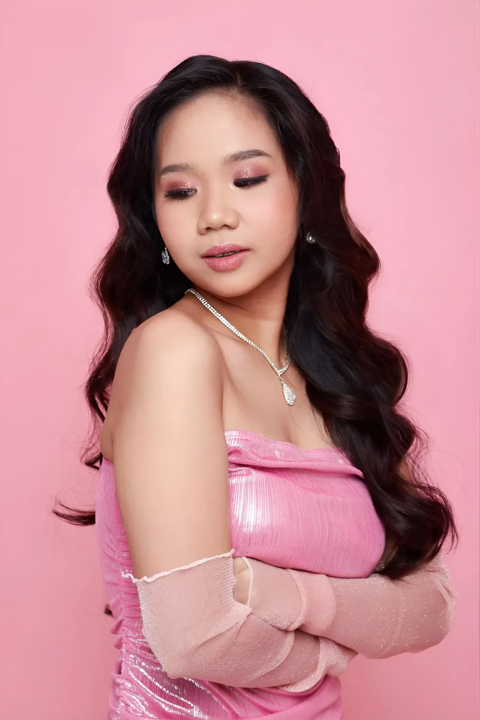 Faye Ramos in pink top with arms crossed against pink background