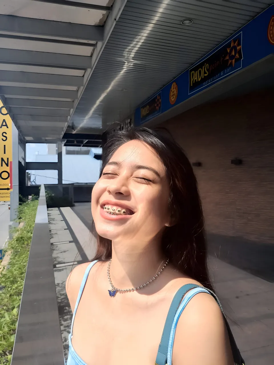 Francesca Ysabelle smiling with eyes closed outdoors near storefront