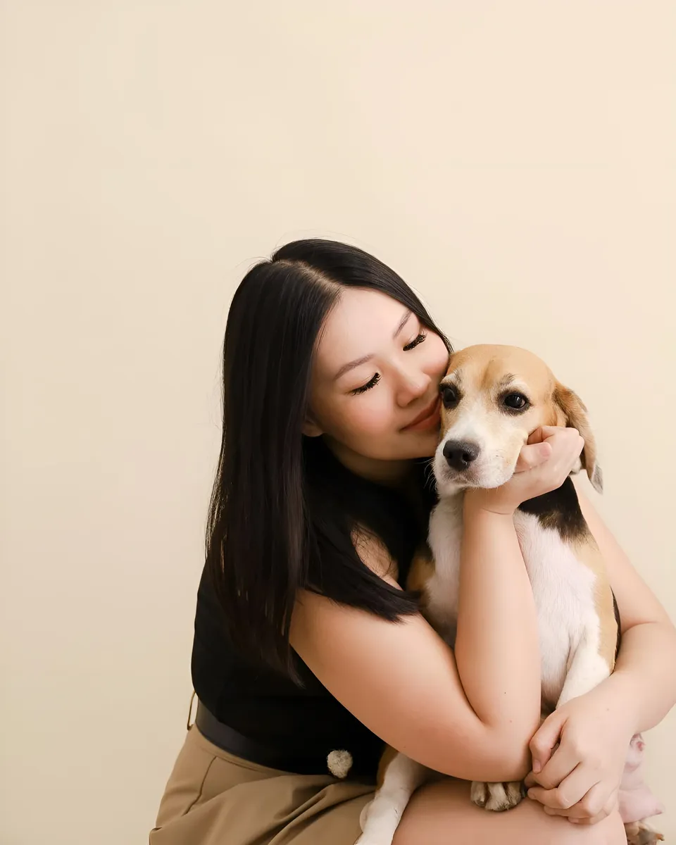 Genelleen Brooks holding small dog in arms against plain background