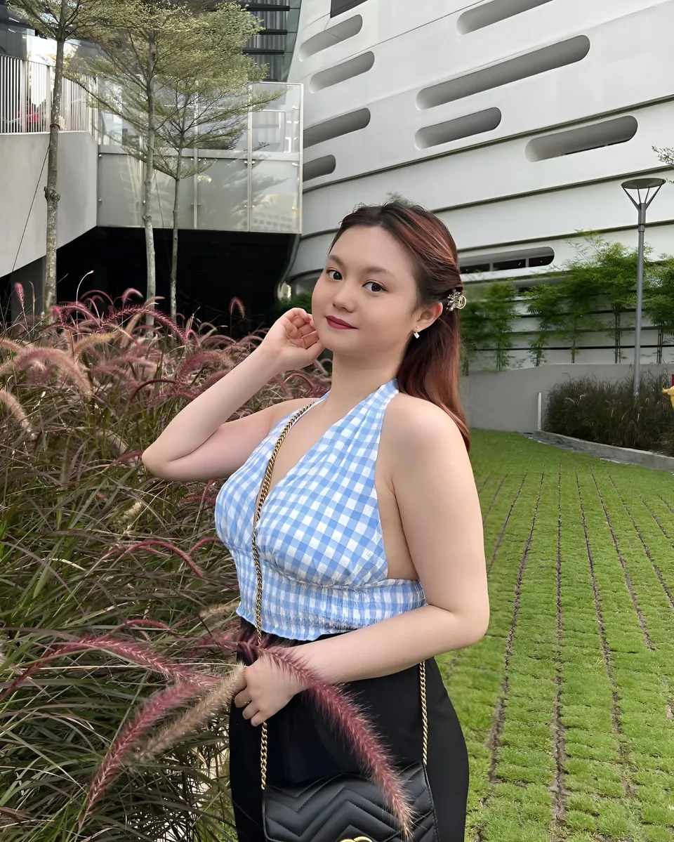 Gigi Laurent in blue checkered top standing outdoors near plants