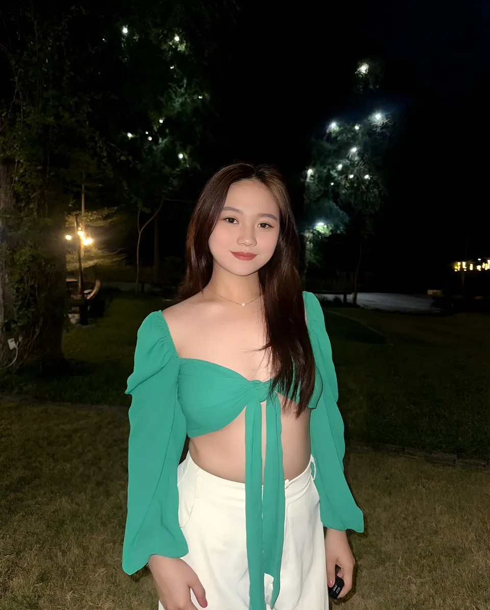 Hangel Delaney wearing a green top and white pants poses outdoors at night