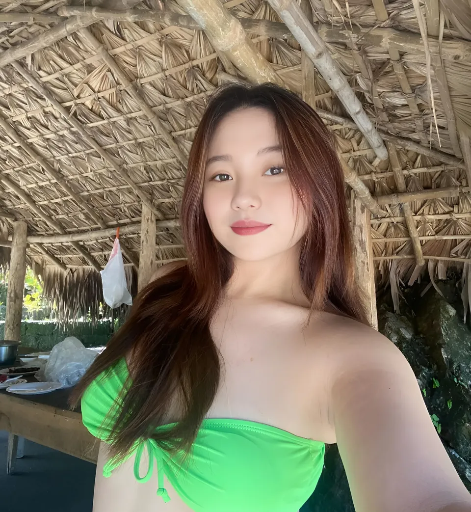 Hangel Delaney in green top taking selfie under thatched roof structure