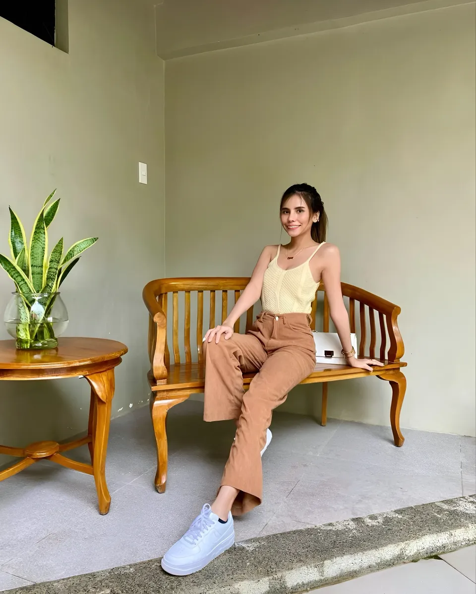 Ica Caparas seated on wooden bench with plant nearby