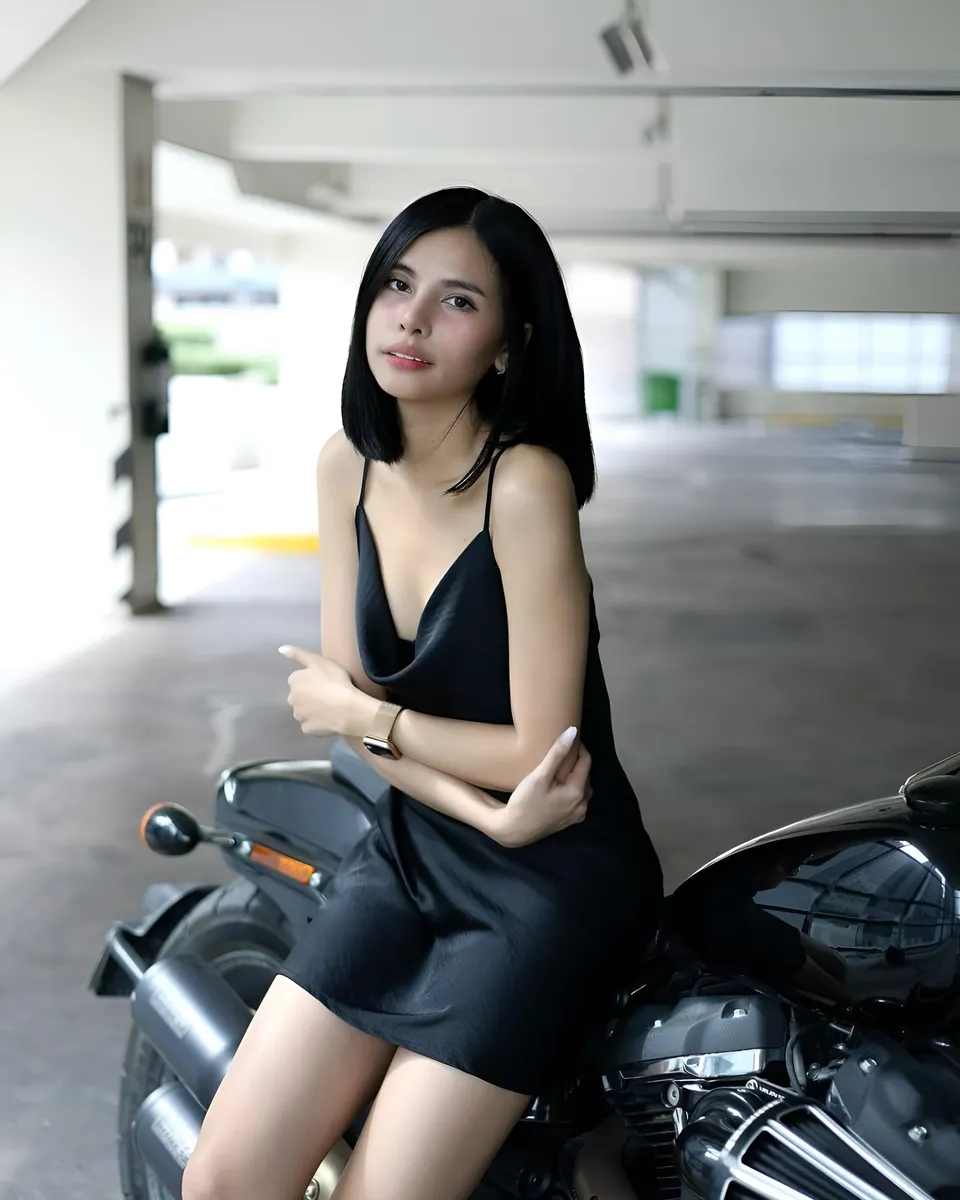 Ica Caparas in black dress seated on motorcycle in parking garage
