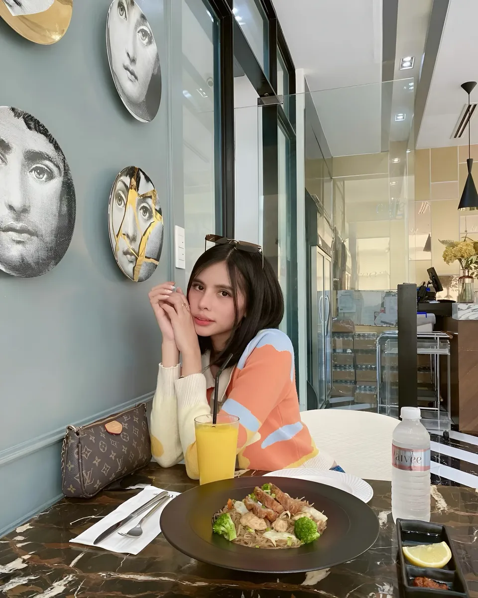 Ica Caparas seated at table with meal and drink
