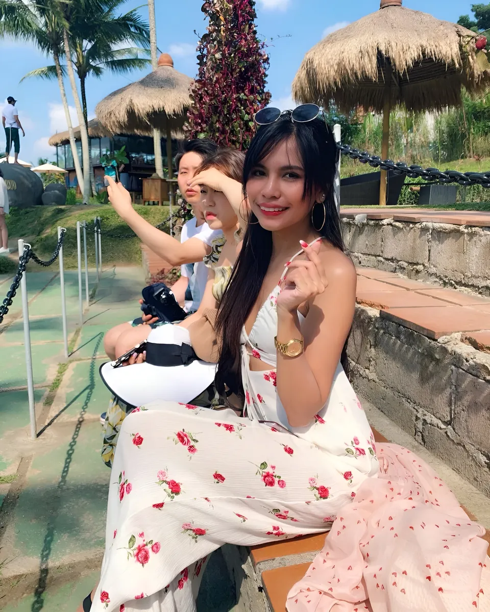 Ica Caparas — Three people seated outdoors near thatched umbrellas and palm trees