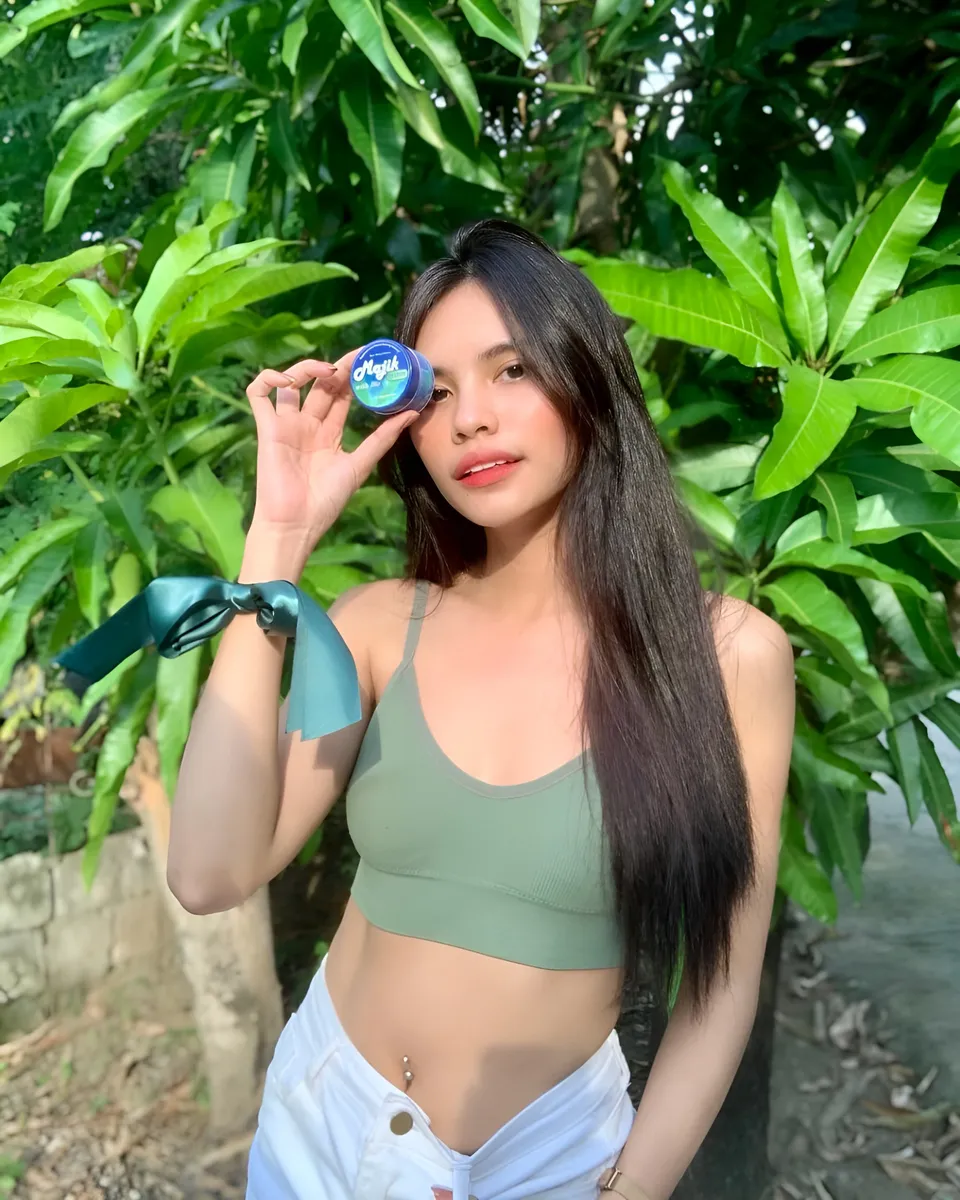 Ica Caparas holding small blue container outdoors with green foliage