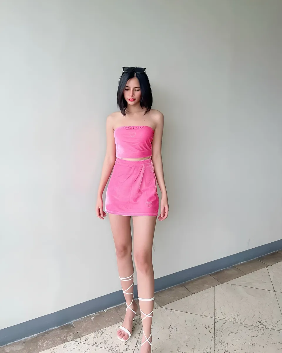 Ica Caparas in pink velvet top and skirt standing against plain wall