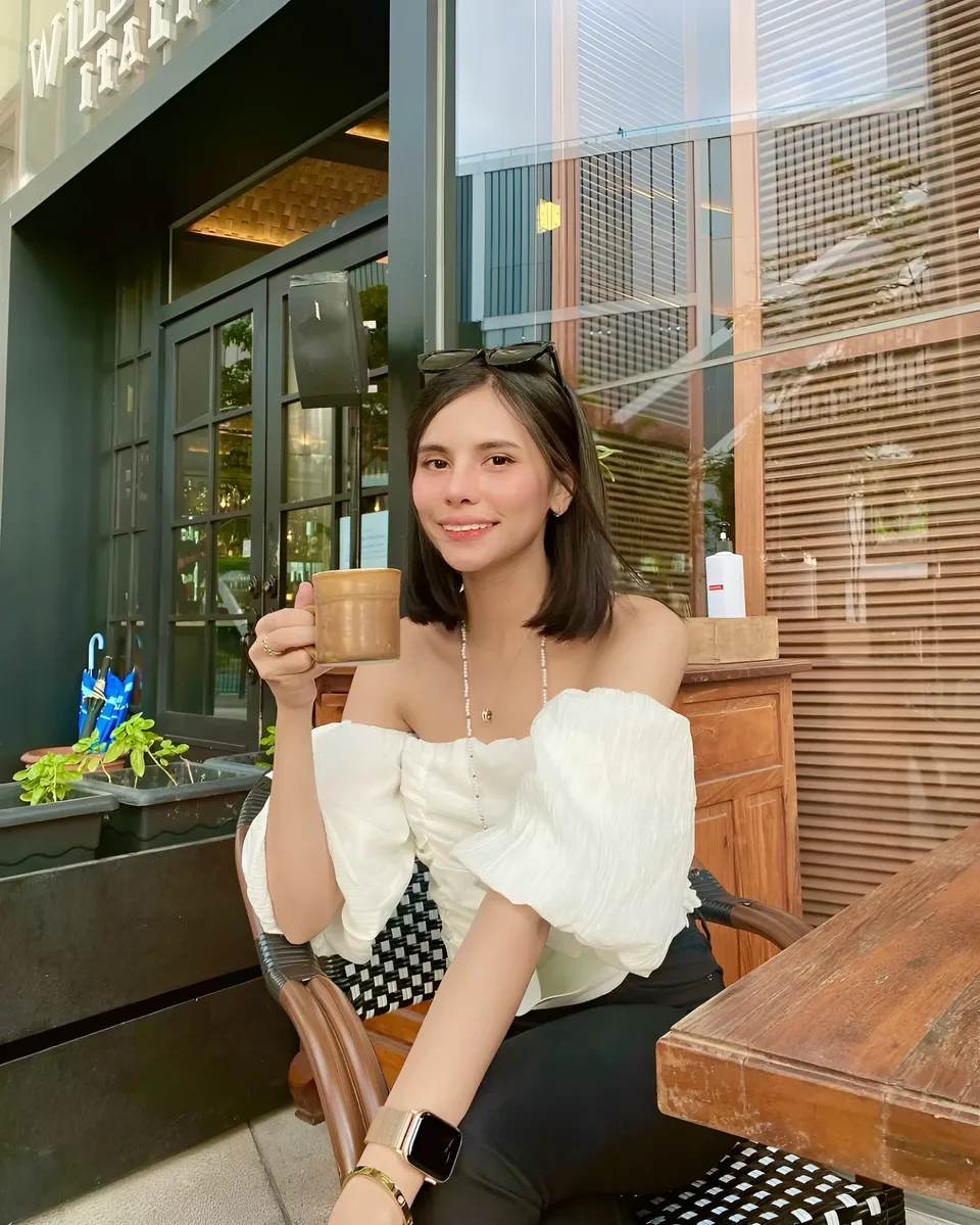 Ica Caparas holding cup seated at outdoor café table