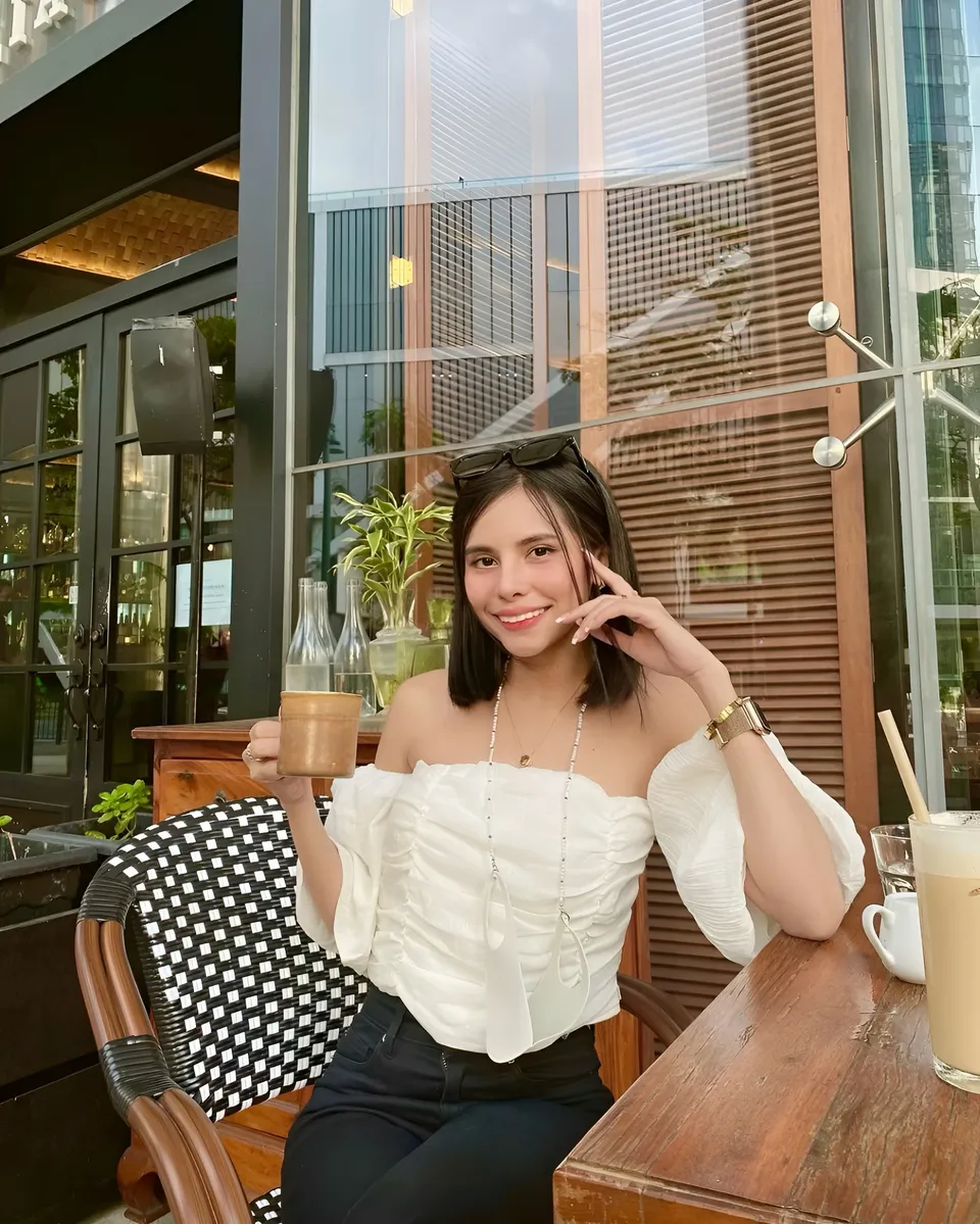 Ica Caparas in white top seated at outdoor café table