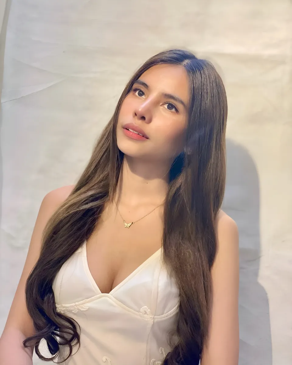 Ica Caparas in white top with long hair, looking up at camera