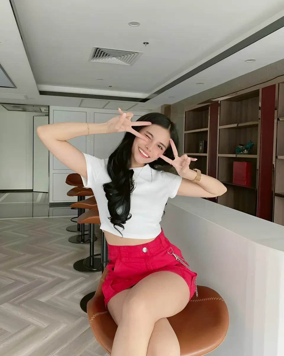 Ica Caparas in white top and red shorts seated on bar stool
