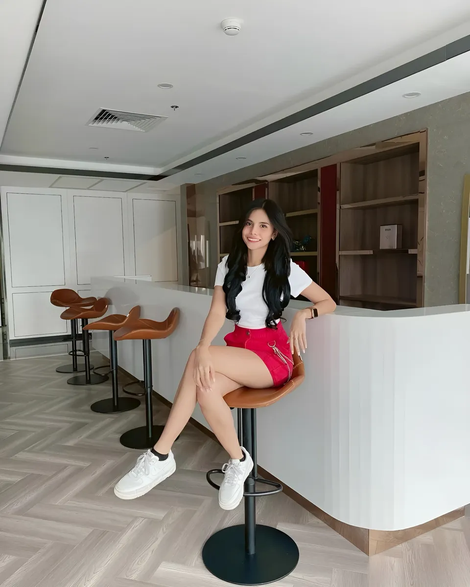 Ica Caparas in white top and red shorts seated on bar stool