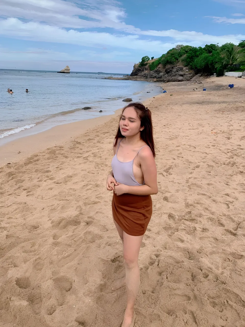 Irish Cruz in purple top and brown skirt standing on sandy beach