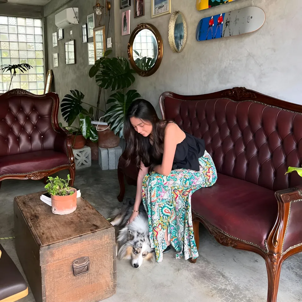 Jainbre Morgan in patterned skirt sits with dog on floor beside sofa