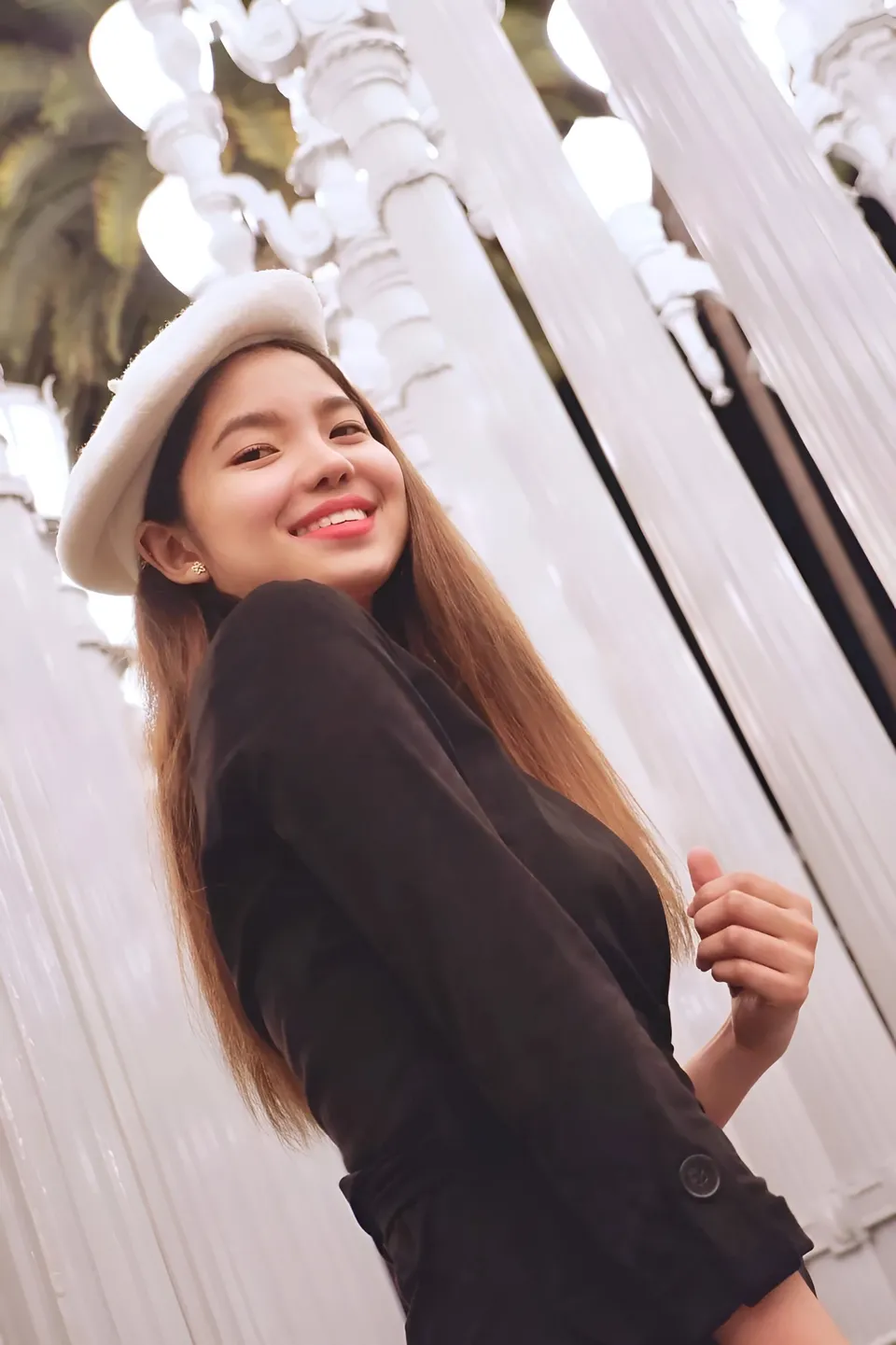 Jann Tiffany Mendoza in black jacket and white hat smiles outdoors