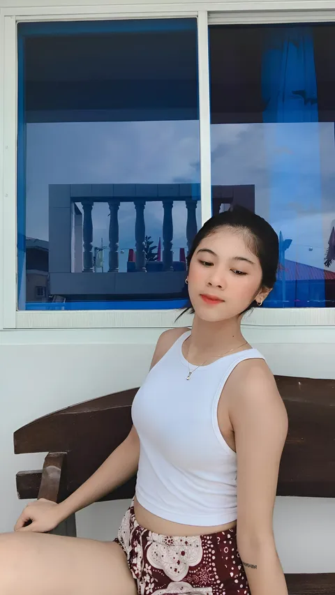 Jansen Hilary Acosta in white top seated on bench near window