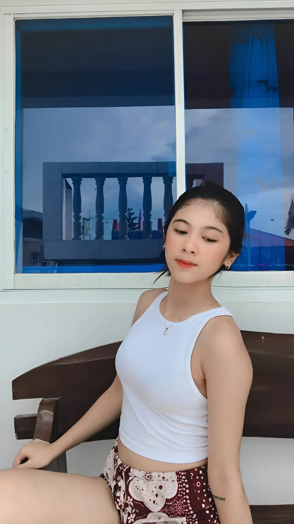 Jansen Hilary Acosta in white top seated on bench near window