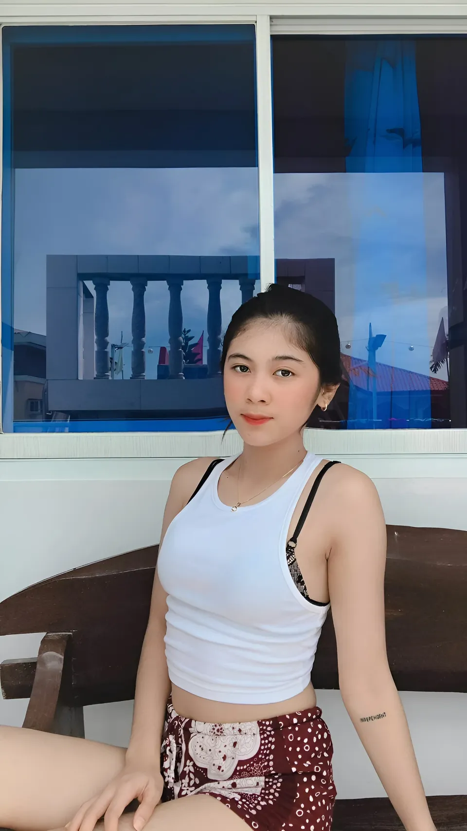 Jansen Hilary Acosta in white top and patterned shorts seated near window