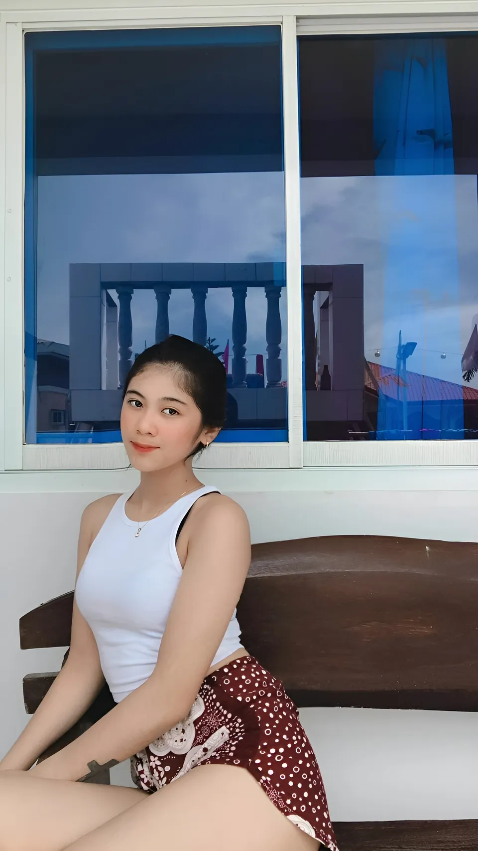 Jansen Hilary Acosta in white top and patterned shorts seated by window