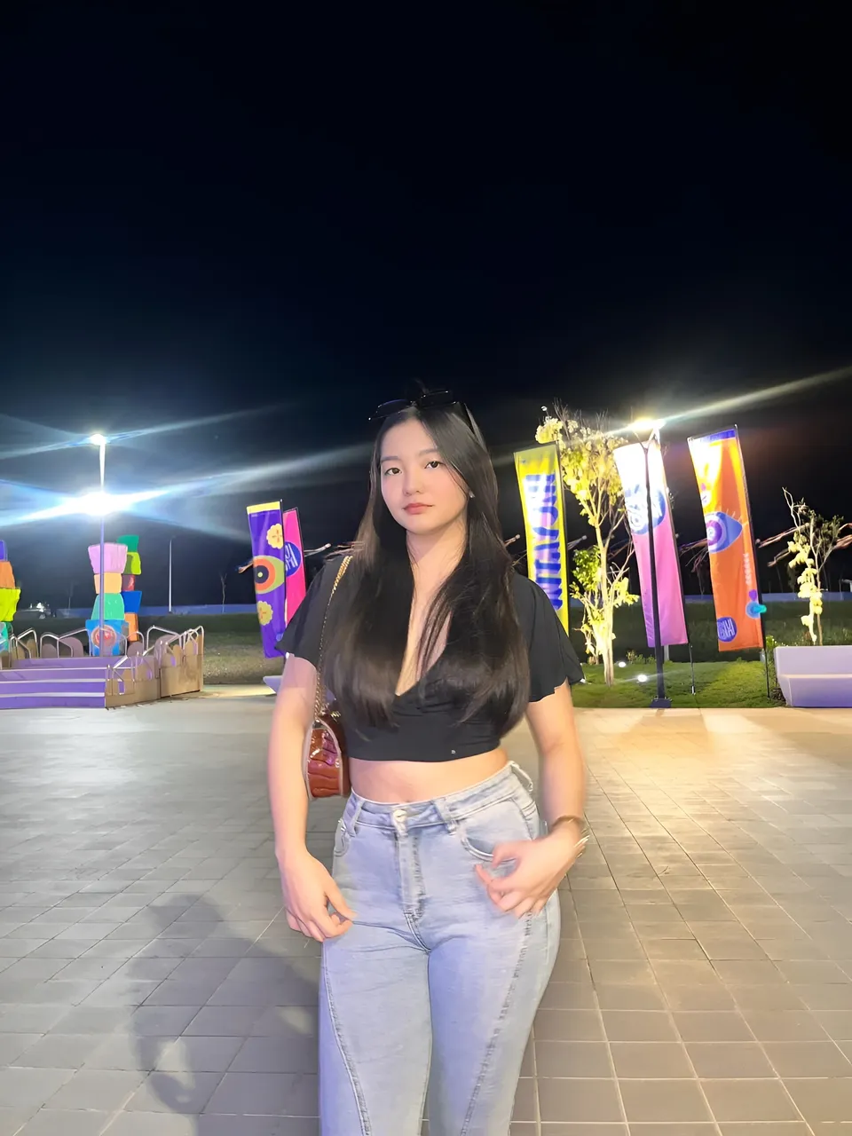 Jazmine Hazel in black crop top and jeans stands outdoors at night