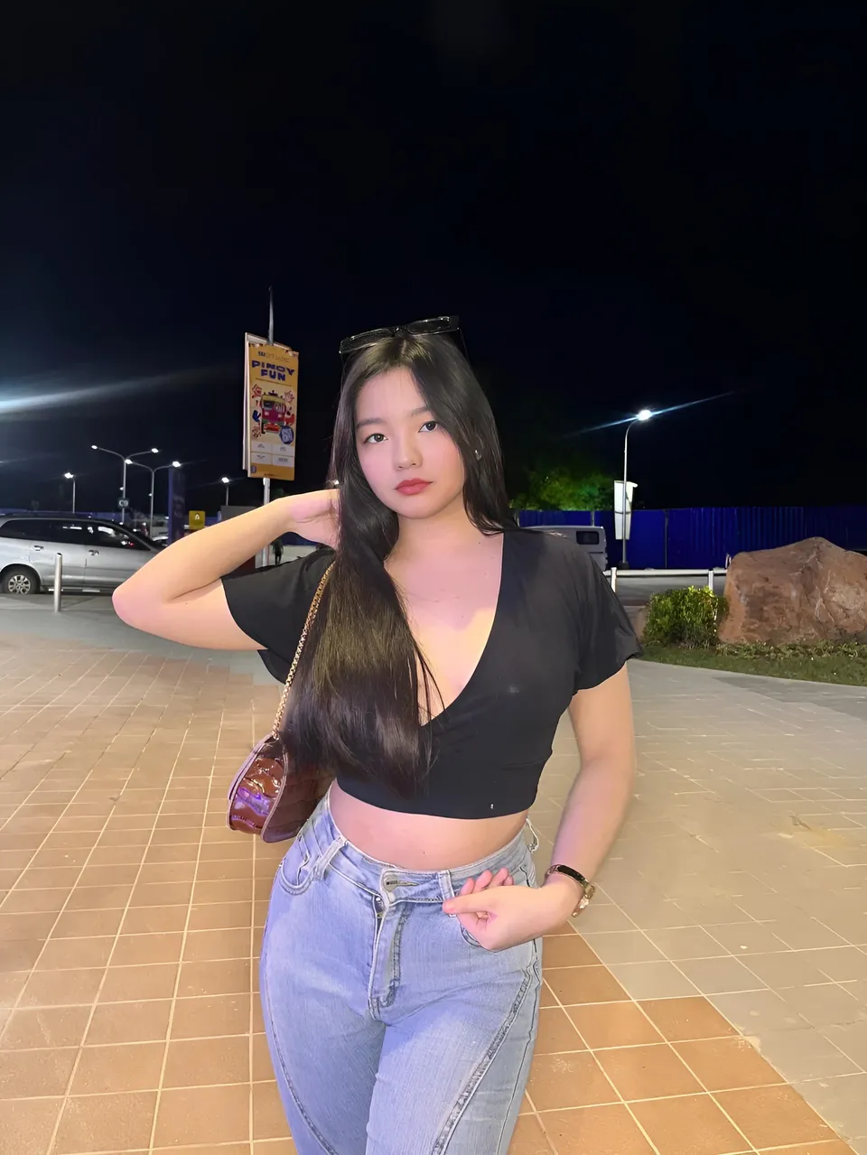 Jazmine Hazel in black top and jeans standing outdoors at night
