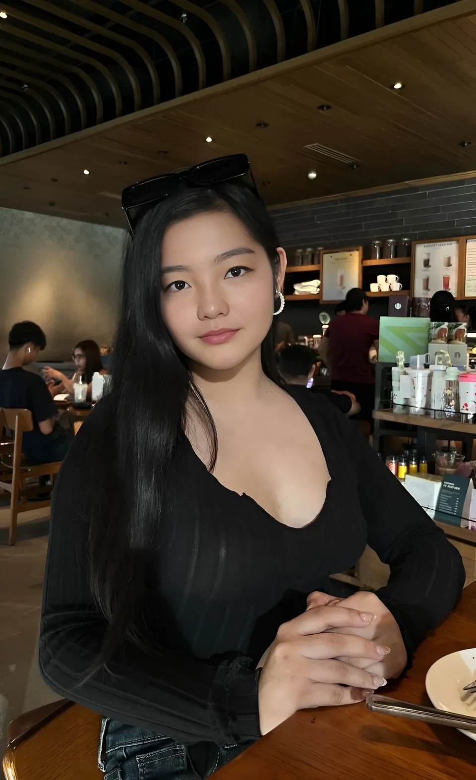 Jazmine Hazel in black top seated at café table