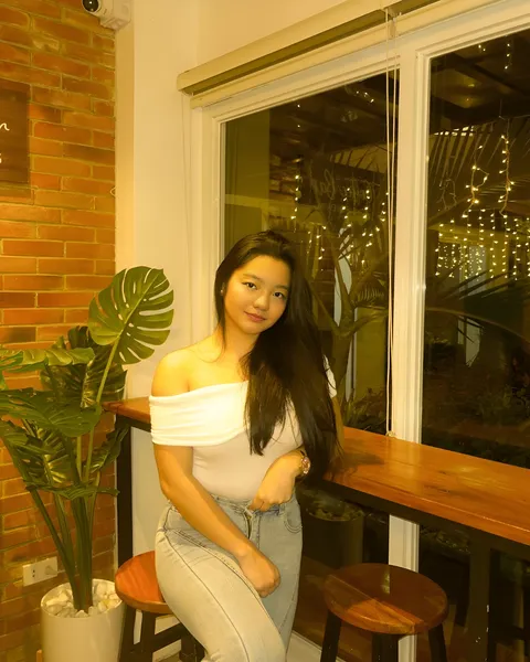 Jazmine Hazel in white top and jeans seated at wooden bar