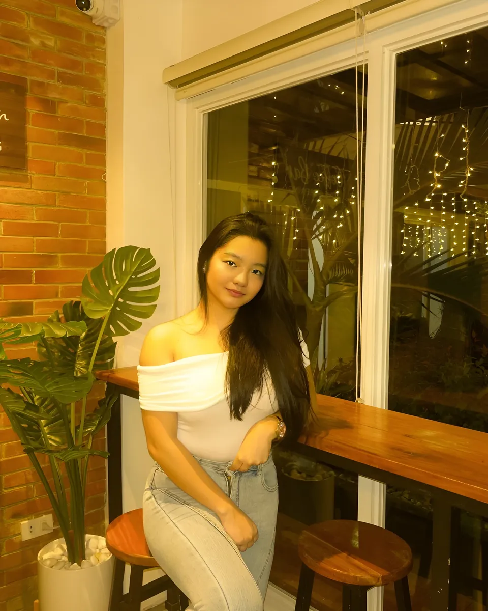 Jazmine Hazel in white top and jeans seated at wooden bar