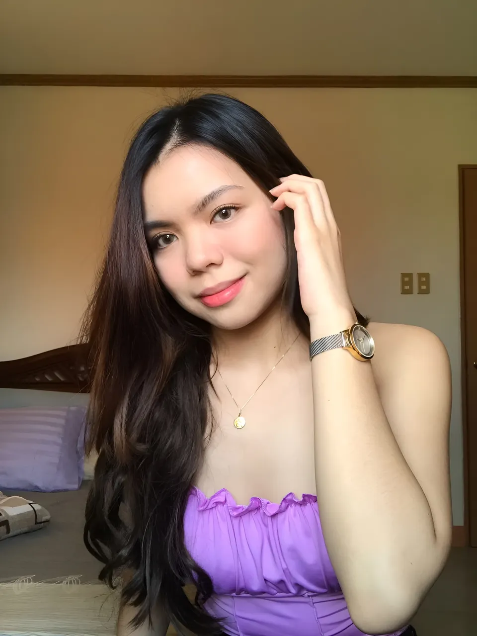 Jeanine Fernandez in purple top with watch and necklace, indoors