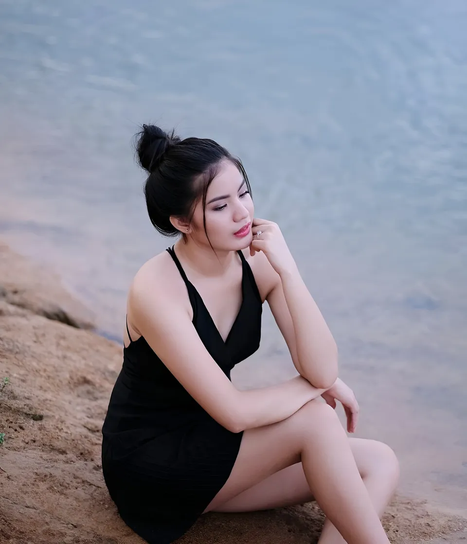 Jennieva Quinn in black dress sitting by water's edge