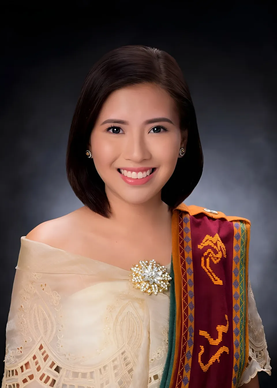 Jessa Bariuan wearing an embroidered shawl and decorative sash poses against a dark background