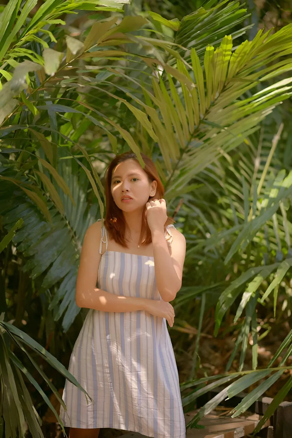 Jessa Bariuan in striped dress standing among green palm fronds