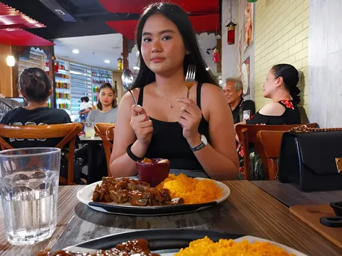 Joanne Cadiente holding fork and spoon at restaurant table