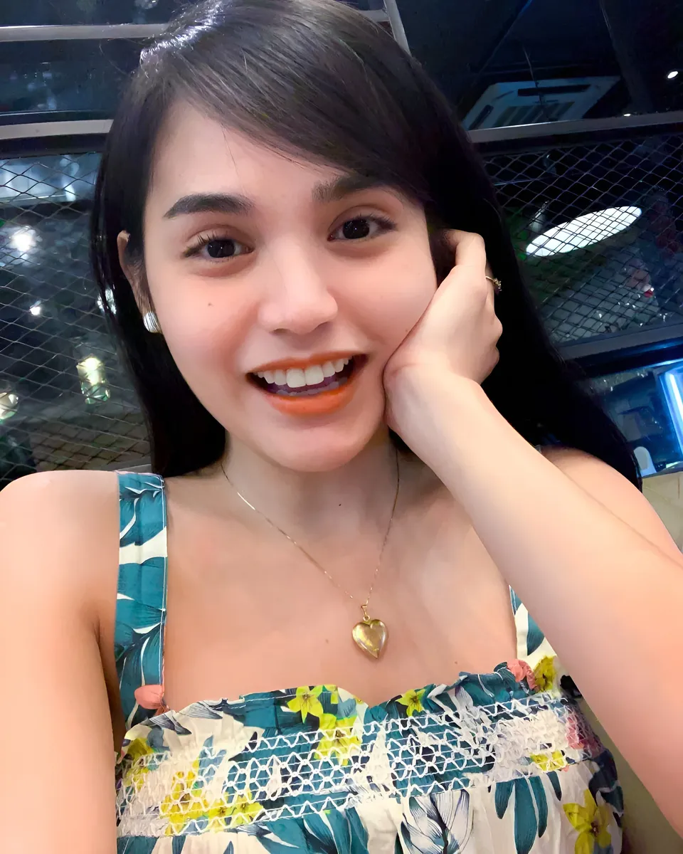 Joey Nerosa smiling in floral top with hand near face