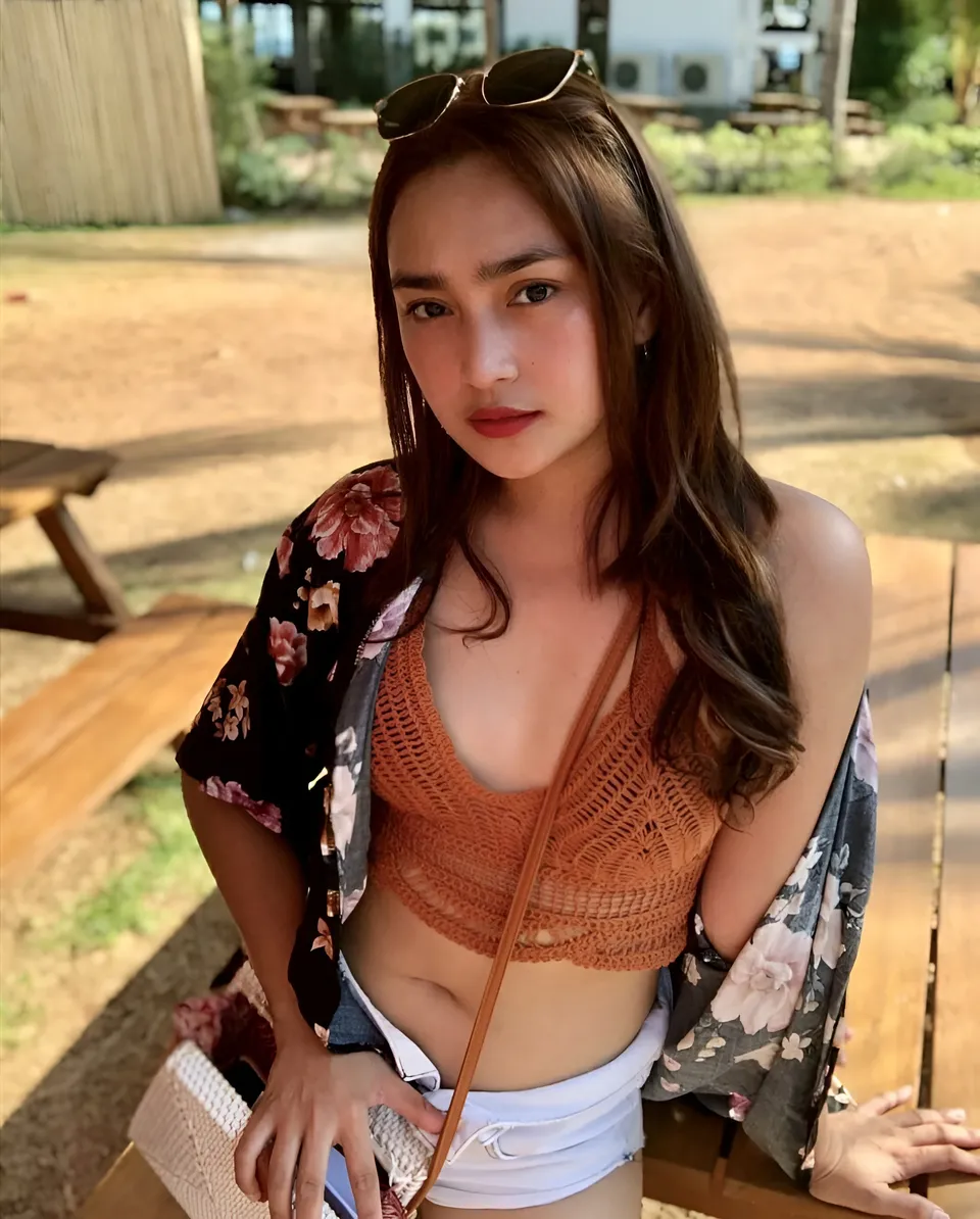 Julia Claire Anne Sotelo wearing orange crochet top and floral jacket seated outdoors