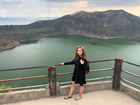 Julia Marlowe wearing a black dress poses beside a railing overlooking a lake