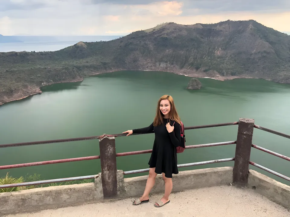 Julia Marlowe wearing a black dress poses beside a railing overlooking a lake