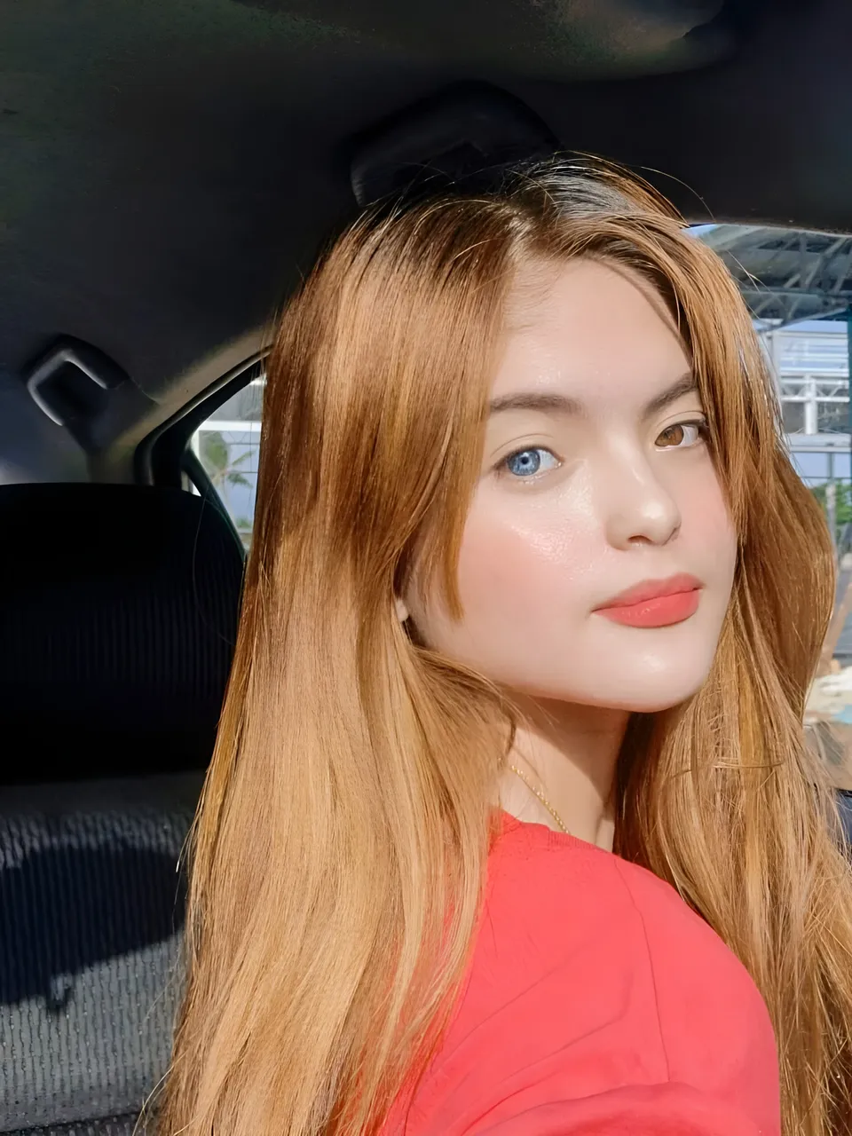 Julia Ostan with long hair wearing red top in car interior