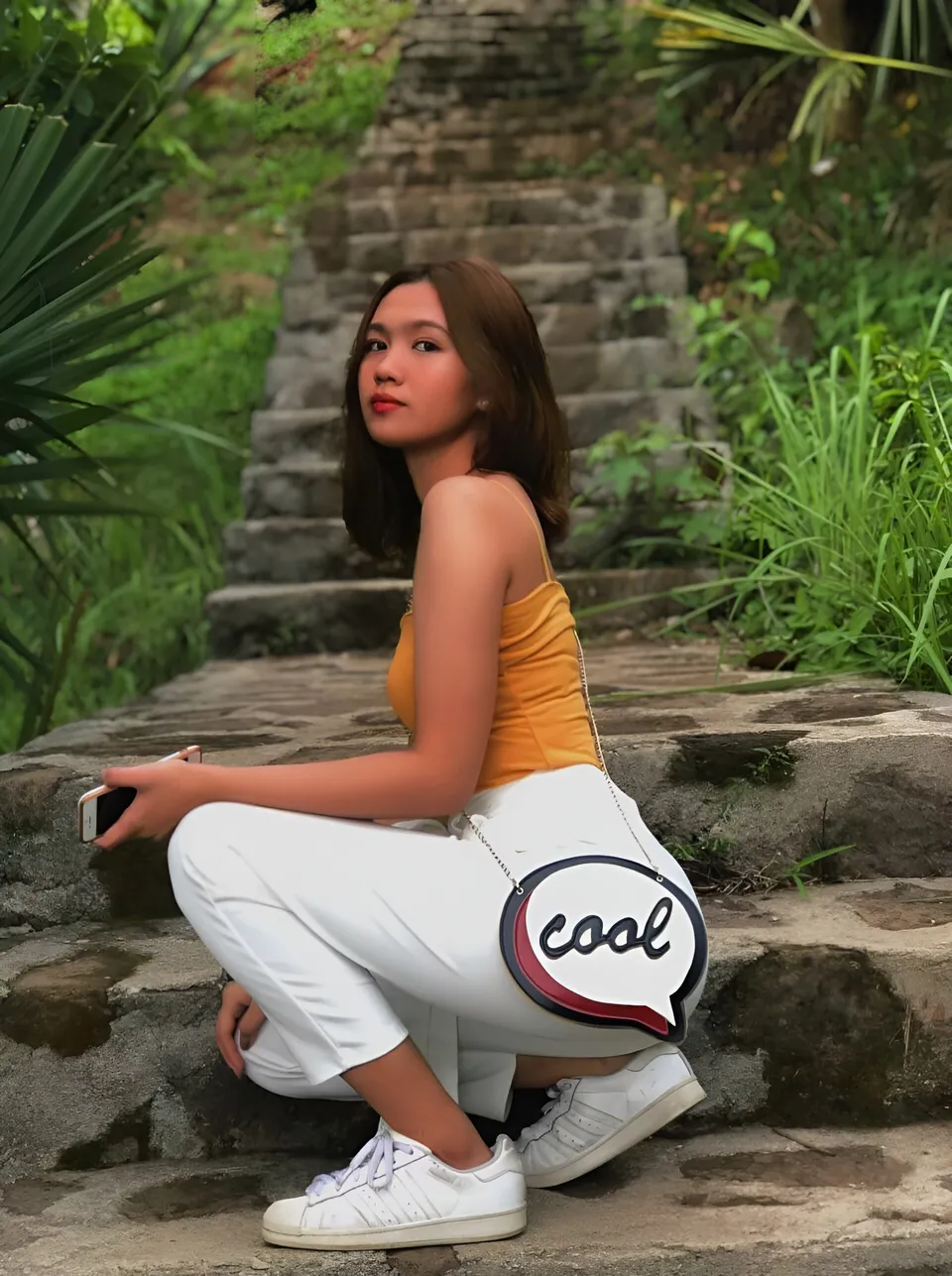 Julia Venturina crouching on stone steps with green foliage around