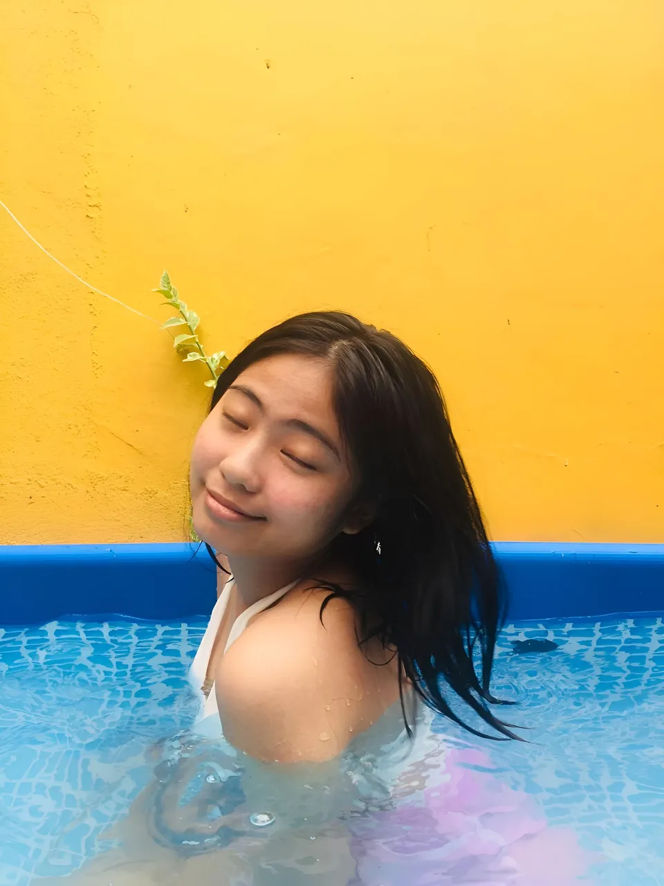 Julian Galan with dark hair smiling in blue pool against yellow wall