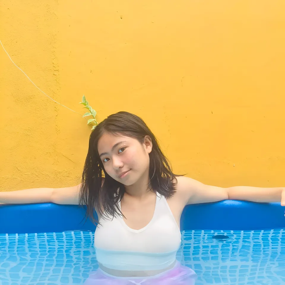 Julian Galan in water with arms out, yellow wall behind