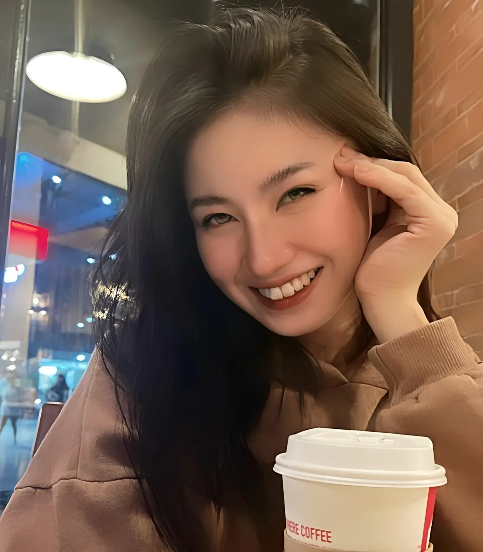 Justine Ponteras smiling with hand near face holding coffee cup